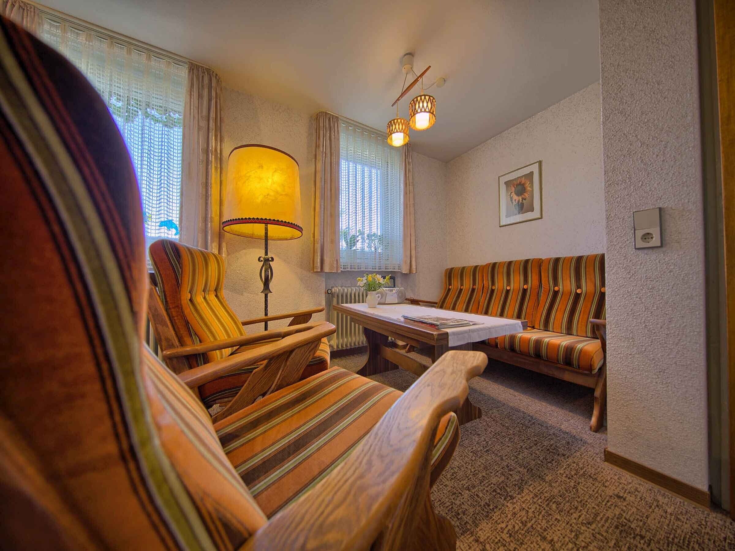 Una habitación acogedora con sillones a rayas, un sofá, una mesa y una lámpara.