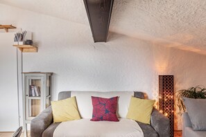 A room with a sofa, cushions, a cabinet, and a wall-mounted light fixture. - Apartment 'Adlerblick' with Mountain View, Balcony and Wi-Fi (Leutasch)