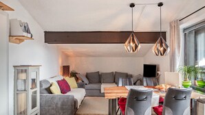 Un espacio de estar moderno con comedor, sofá y televisor.
