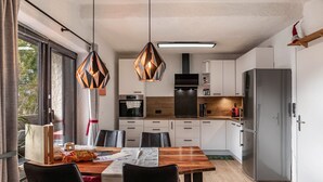 Una cocina moderna con comedor, que incluye una mesa de madera, sillas negras y lámparas colgantes.