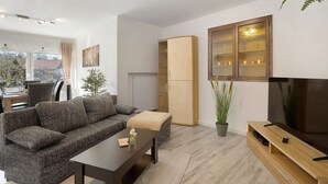 Una sala de estar moderna con sofá, mesa de centro, mueble para televisor y un armario.