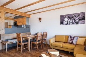 En modern inredning med ett matbord och stolar i trä, en soffa och en tavla med åsnor som hänger på väggen.