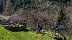 A playground with swings, a covered seating area, and a small building with a sloped roof. - Holiday Apartment "Kuhgeflüster" – 5 Stars (Titisee-Neustadt)