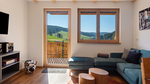 A living room with a sofa, a television, a wooden stool, and a cow-shaped ottoman. - Holiday Apartment "Kuhgeflüster" – 5 Stars (Titisee-Neustadt)