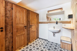 A bathroom with wooden doors, a white sink, and a tiled floor.