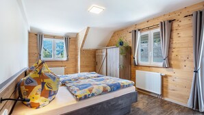 Een slaapkamer met een bed, een raam, een radiator en een tas op het bed.