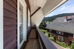 Ein Balkon mit Blick auf ein Wohngebiet, eine Holzfassade und ein Fenster.