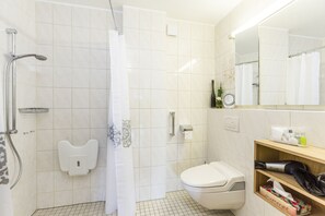 Une salle de bain avec une douche, des toilettes et une étagère contenant des articles de toilette.