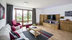 A modern living room with a sofa, a coffee table, a TV, and a wooden cabinet. - Apartment 'With 78 sqm' with Private Terrace and Wi-Fi (Höchenschwand)