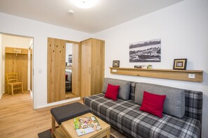 Une pièce comprenant un canapé, un banc, une armoire en bois, un miroir et une étagère murale ornée de tableaux.