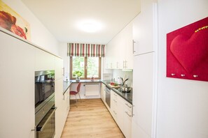Une cuisine moderne avec des armoires blanches, un plan de travail en bois et un décor en forme de cœur rouge.