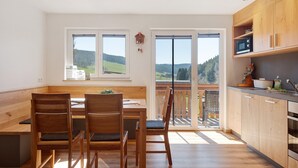 Eine moderne Küche mit Holzausstattung, einem Essbereich mit einer Bank und großen Fenstern mit Blick ins Freie.