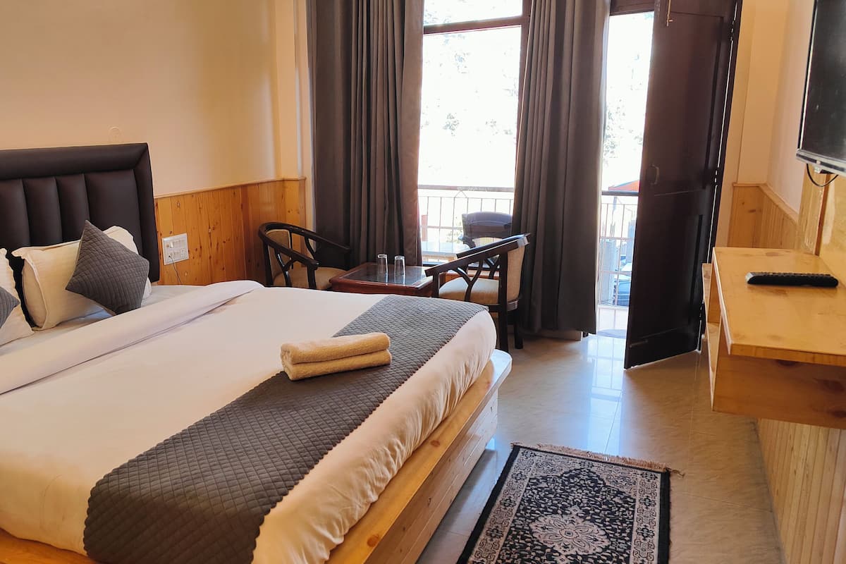A hotel room with a large bed, a wooden headboard, a desk with a chair, and a TV.