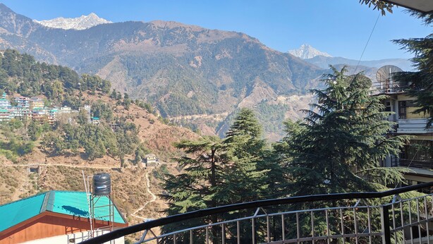 A mountainous landscape with a view of a valley and a building with a blue roof. - HOTEL CLOUD HEIGHT (Dharamshala)