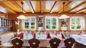 A dining area with wooden furniture, a long table set for a meal, and large windows with a view of greenery. - Apartment '6' with Mountain View, Balcony and Wi-Fi (Sankt Blasien)