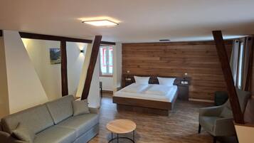 Ein Schlafzimmer mit einem Bett, einem Sofa, einem runden Tisch und Holzvertäfelung an den Wänden.