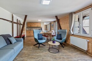 A modern interior with a sofa, two armchairs, a small table, and a potted plant.