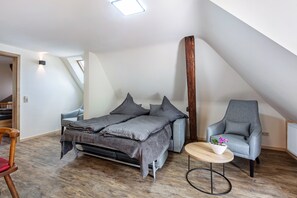 Dormitorio estilo loft con cama, una silla, una mesita y una viga de madera.