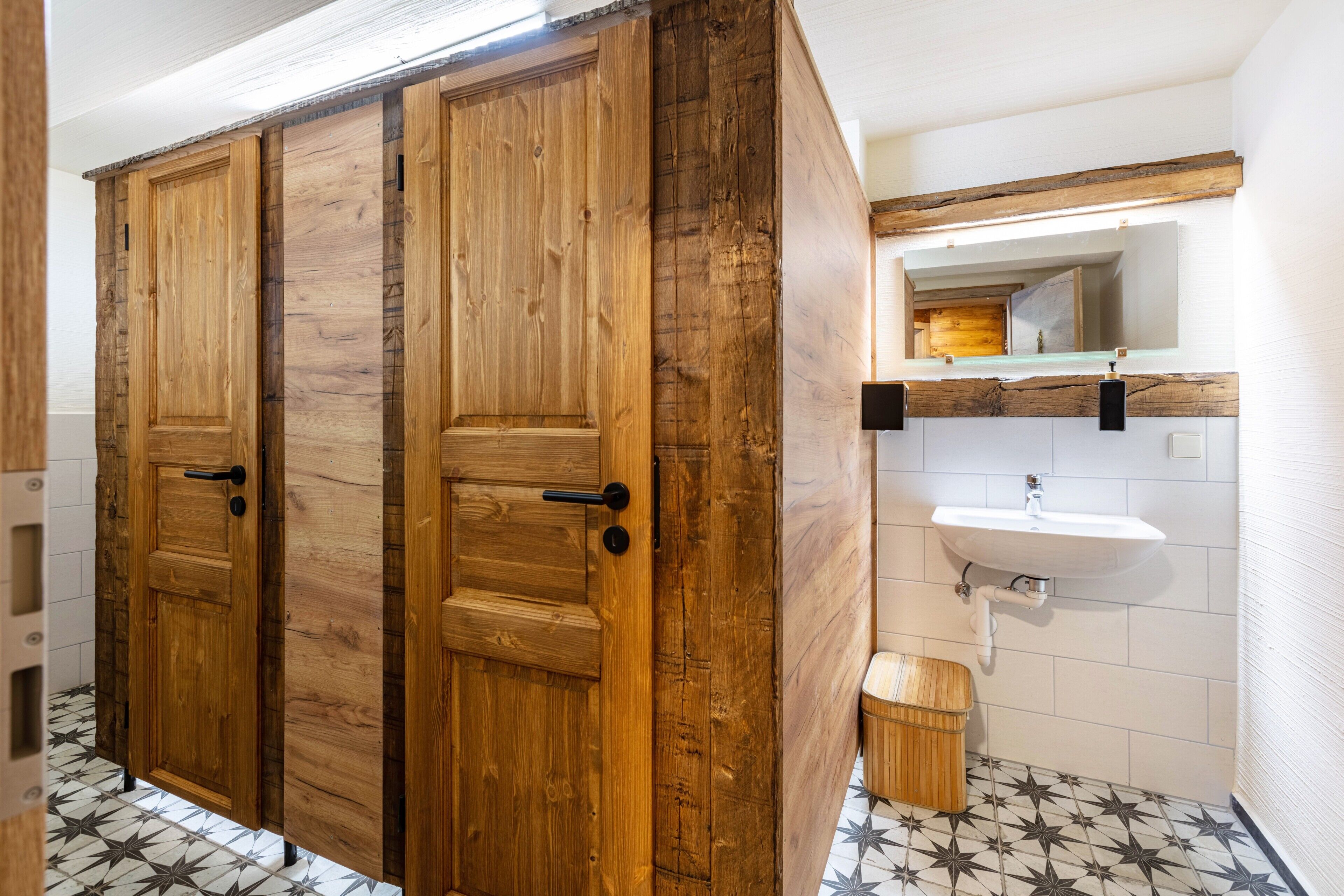 Een badkamer met houten kastjes, een wastafel en een betegelde vloer.