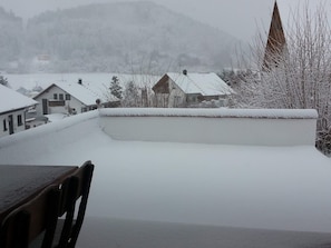 Un barrio residencial cubierto de nieve, con casas y la aguja de una iglesia.
