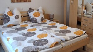 Une chambre à coucher avec un lit, une armoire, un miroir et un tableau accroché au mur.
