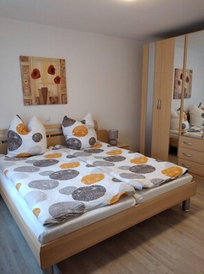A bedroom with a bed, a wardrobe, a mirror, and a painting on the wall.