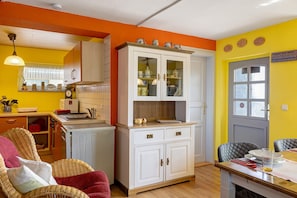 A kitchen with white cabinets, a dining table with chairs, and a window with curtains.