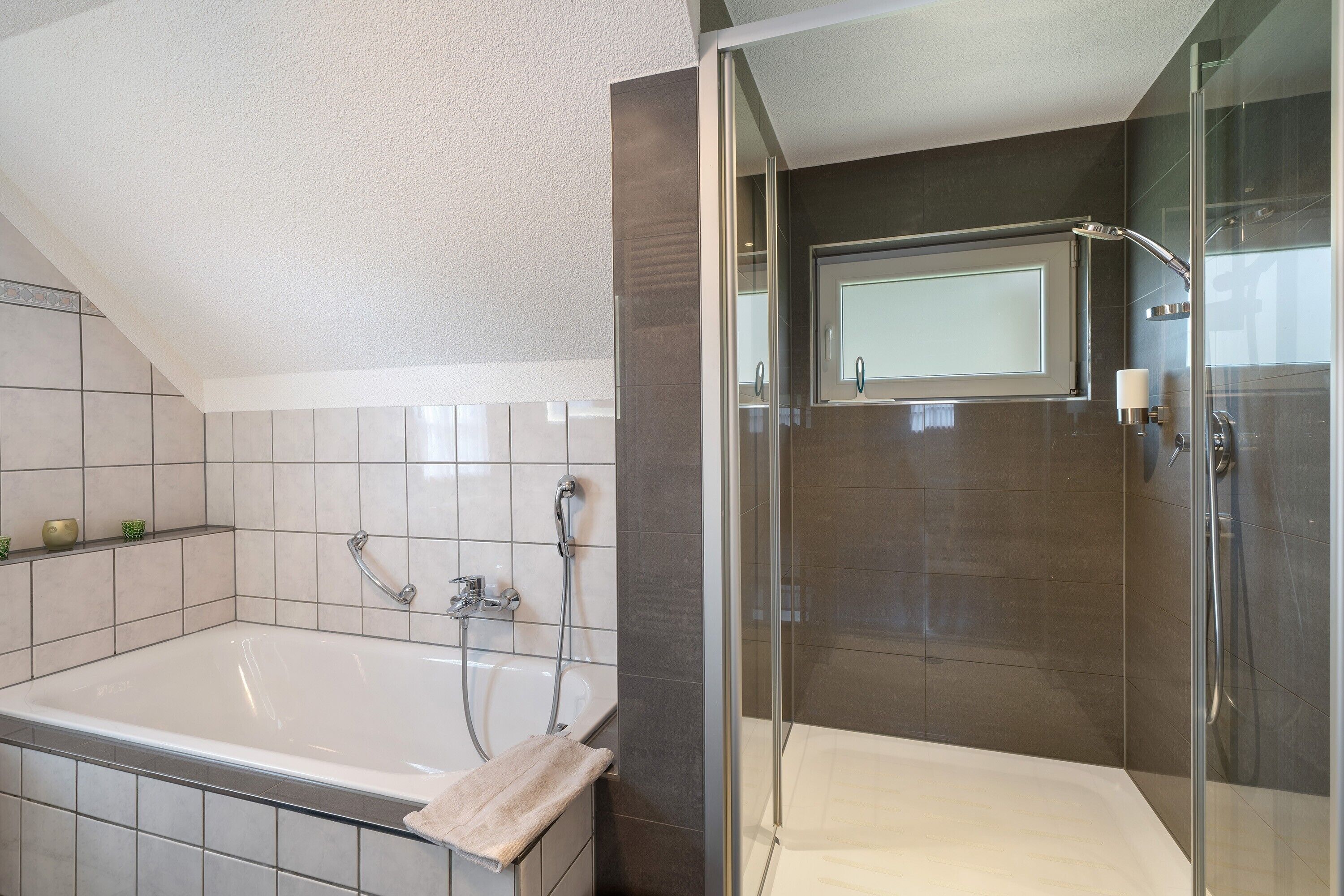 A modern bathroom with a bathtub, shower, and glass-enclosed shower stall.