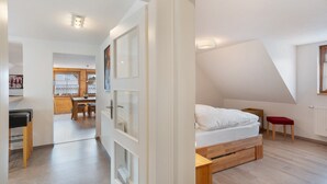 Ein modernes Schlafzimmer mit Schlafplatz in der Loggia, einem kleinen Holztisch und einer roten Bank.