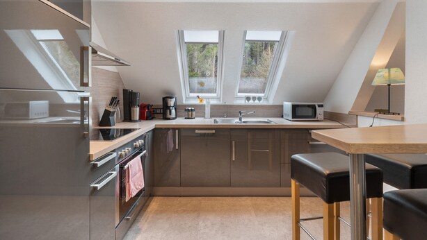Eine moderne Küche mit eingebautem Backofen, Mikrowelle und einem großen Fenster.