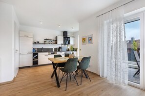 A modern kitchen with white cabinets, a wooden dining table, and two chairs. - Apartment 'Weitblick' with Mountain View (Winterberg)