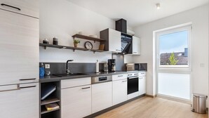 A modern kitchen with built-in appliances, a window, and a view of the outside. - Apartment 'Weitblick' with Mountain View (Winterberg)