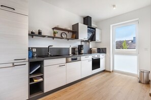 Une cuisine moderne dotée d’appareils électroménagers intégrés, d’une fenêtre et offrant une vue sur l’extérieur.