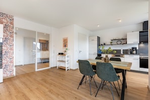 Una cocina moderna con armarios blancos, una mesa de comedor de madera y dos sillas.