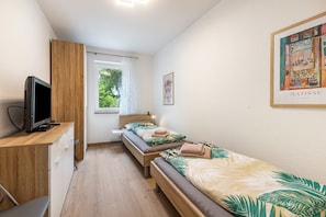 A bedroom with two beds, a TV, a desk, and a window with curtains. - Apartment 'Weitblick' with Mountain View (Winterberg)