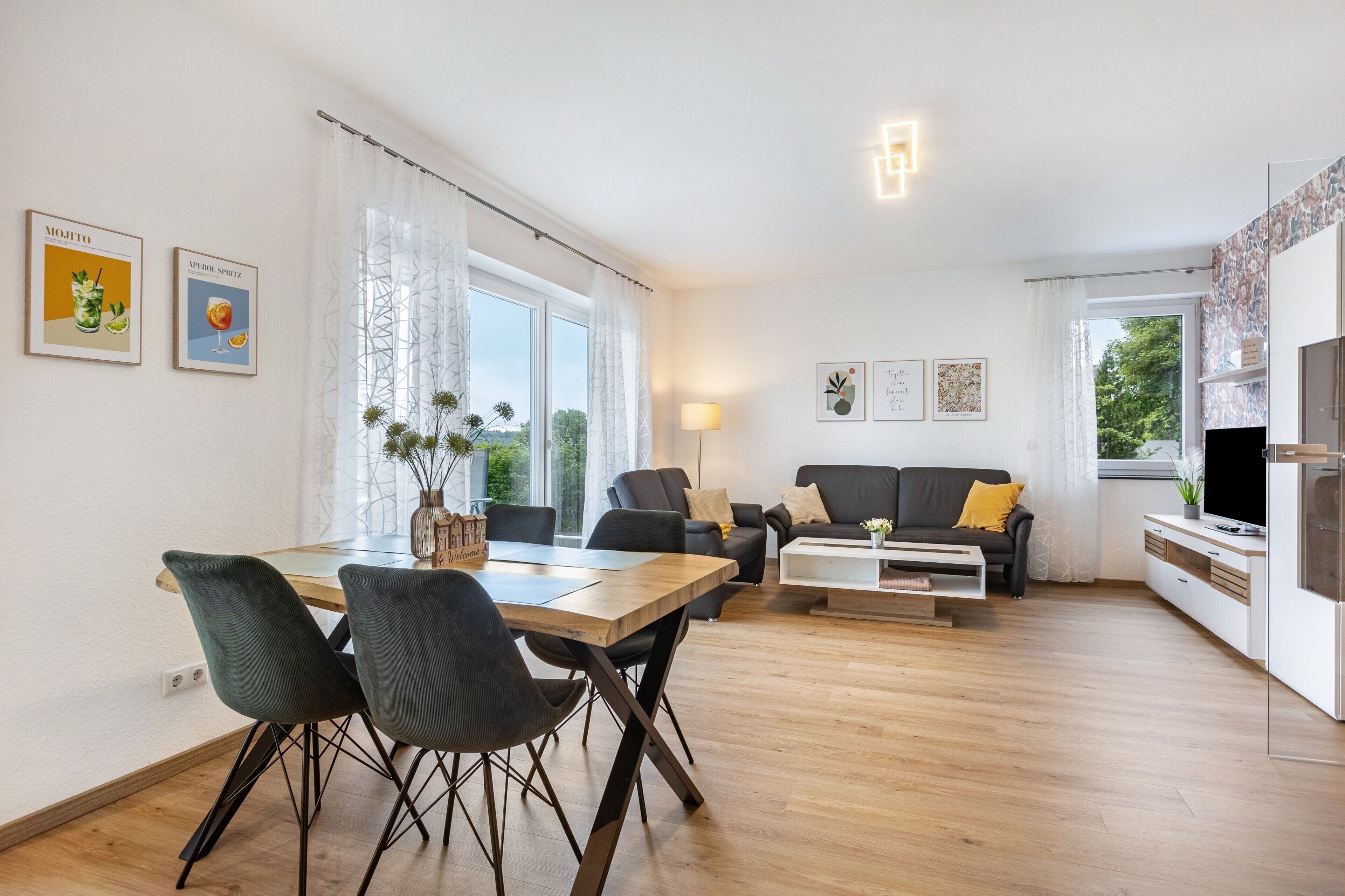 Uma sala de estar moderna com área de jantar, sofá, televisão e lareira.