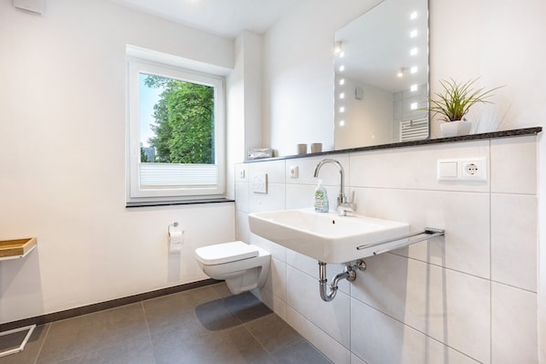 Un baño moderno con inodoro, lavamanos y ventana.