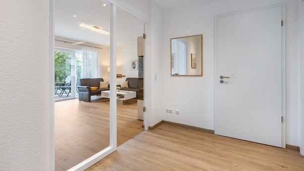 A modern living room with a sofa, coffee table, and a large mirror on the wall. - Apartment 'Weitblick' with Mountain View (Winterberg)