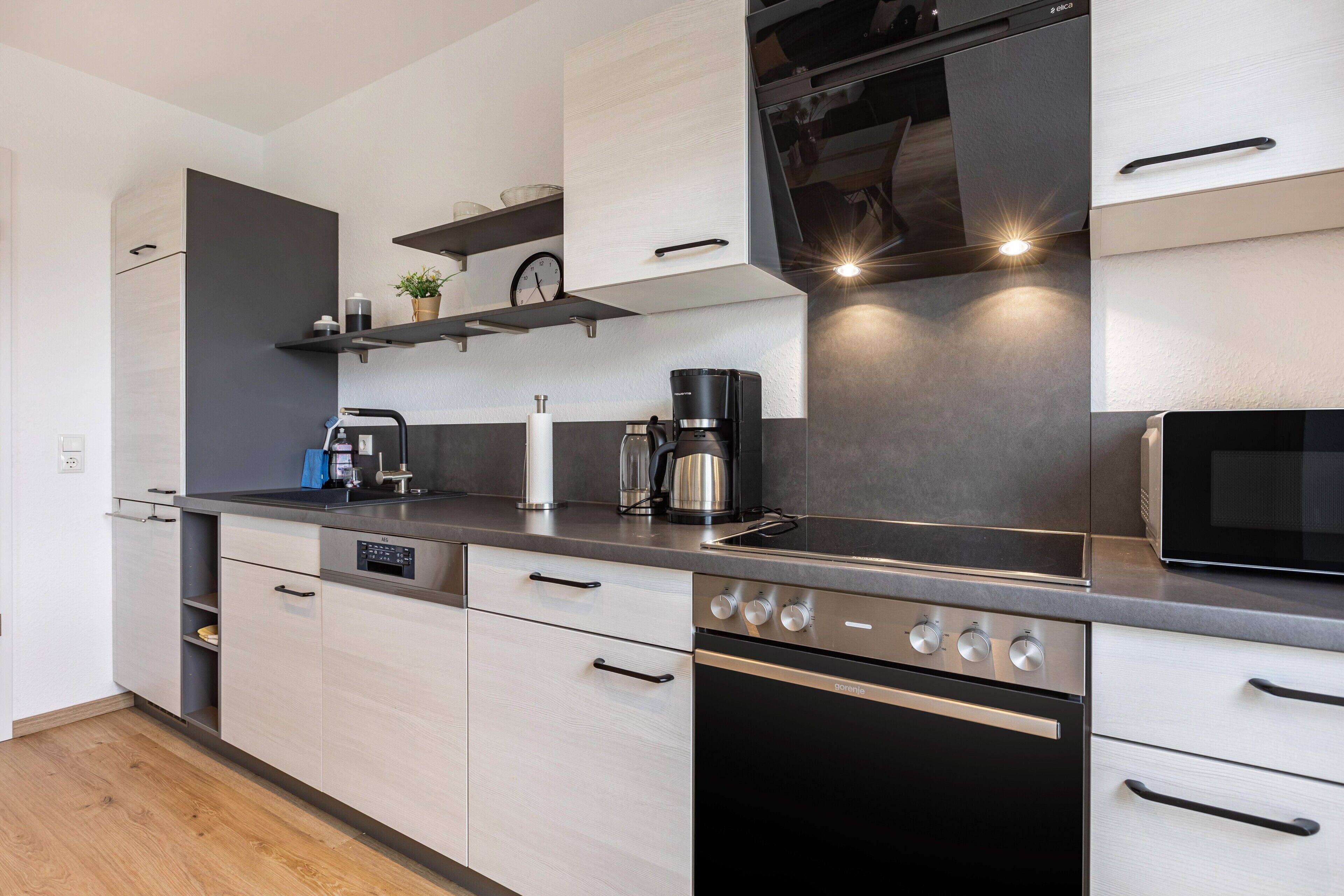 A modern kitchen with a built-in oven, a coffee maker, and a microwave.