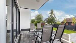 A patio with outdoor furniture, a glass door, and a view of a residential area. - Apartment 'Weitblick' with Mountain View (Winterberg)