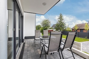 Un patio con mobiliario exterior, una puerta de vidrio y vistas a una zona residencial.
