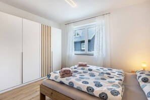 A bedroom with a bed, bedside tables, a window, and a wardrobe.