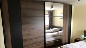 Un dormitorio con cama, mesita de noche, espejo y armario.