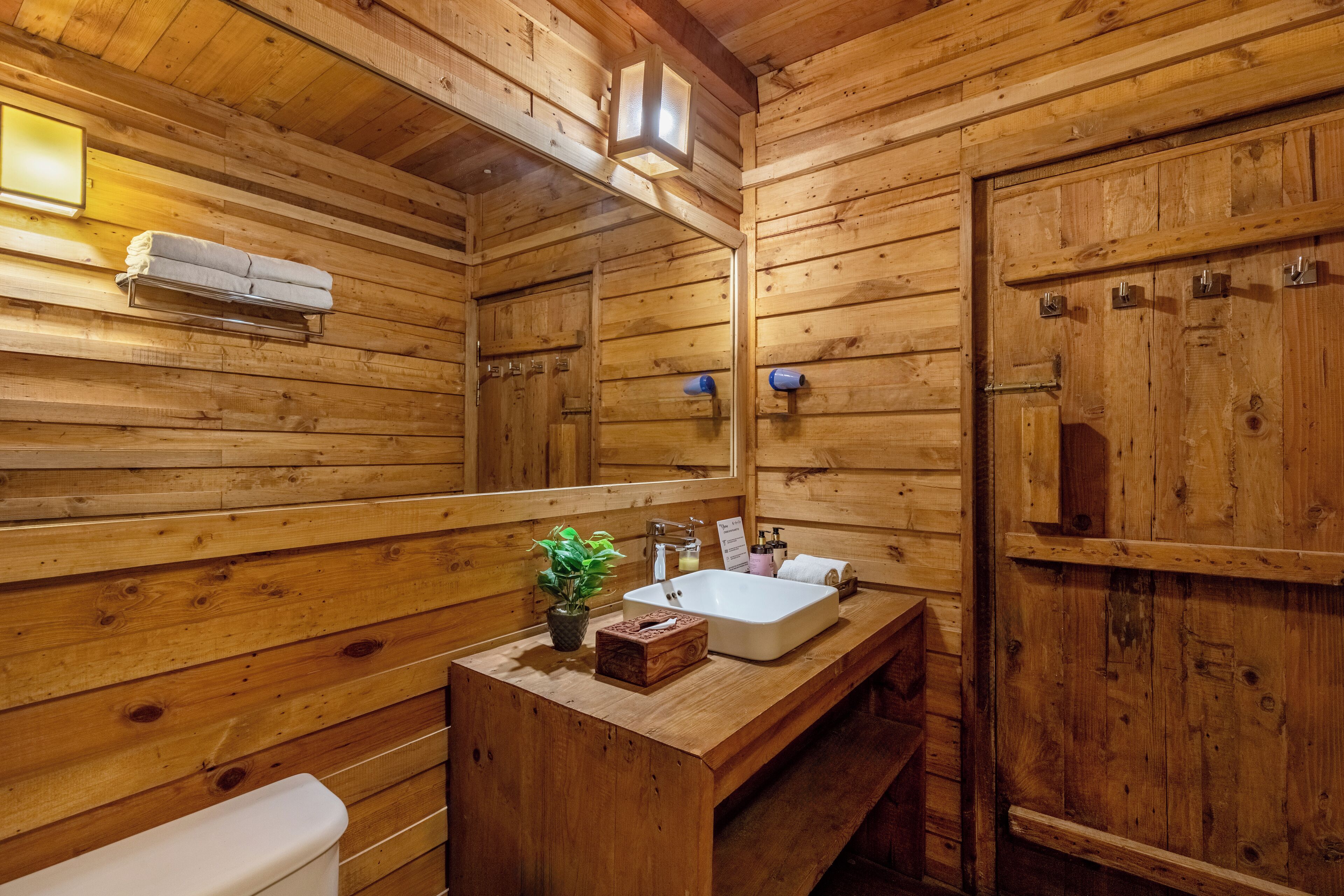 A wooden cabin bathroom with a wooden sink, a towel rack, and a mirror.