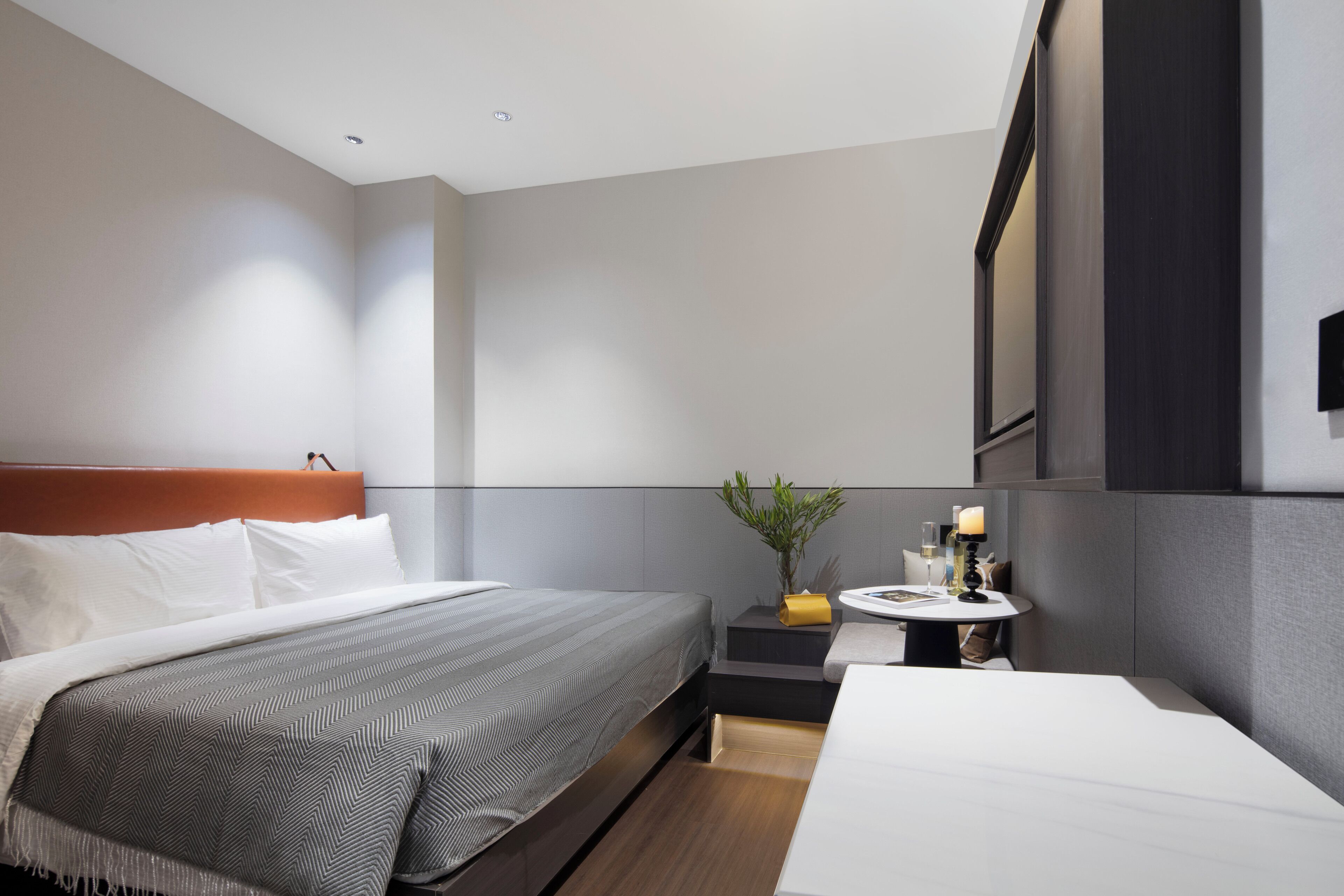 Een moderne hotelkamer met een groot bed, een nachtkastje met een lamp en een zithoekje.