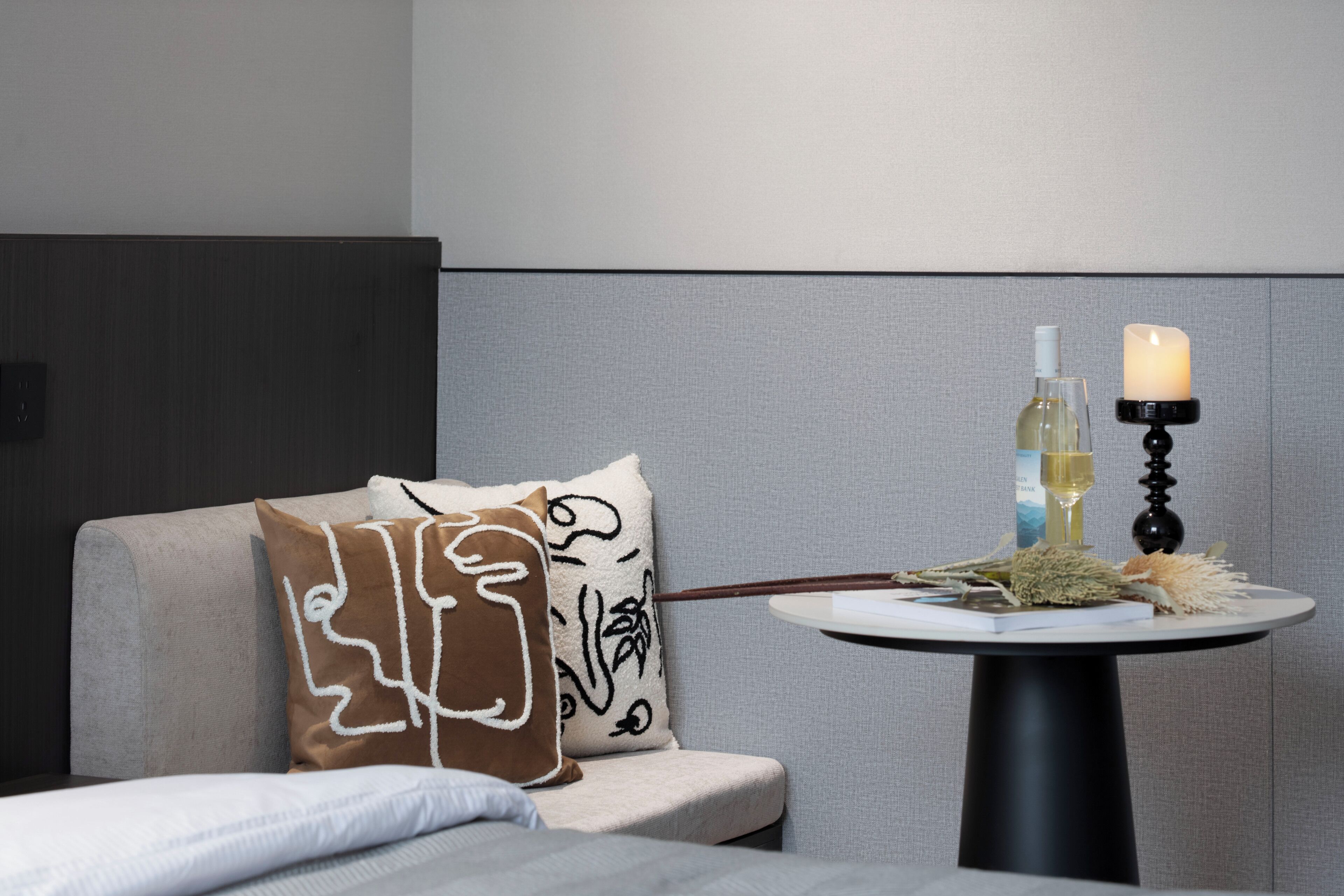A modern room with a grey sofa, a round table with a candle, and decorative items.