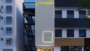 Eine moderne Hotelansicht mit einem gut sichtbaren 'mcsrh'-Schild, einem einladenden Eingang und einer Treppe, die zu einer oberen Etage führt.