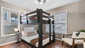 Ein Zimmer mit einem Stockbett, einem Schreibtisch, einem Stuhl und einer Lampe.