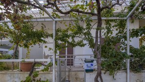 A covered outdoor area with a metal gate, potted plants, and a staircase leading to a building entrance. - Alisahni Home 2, Villa (Chania)
