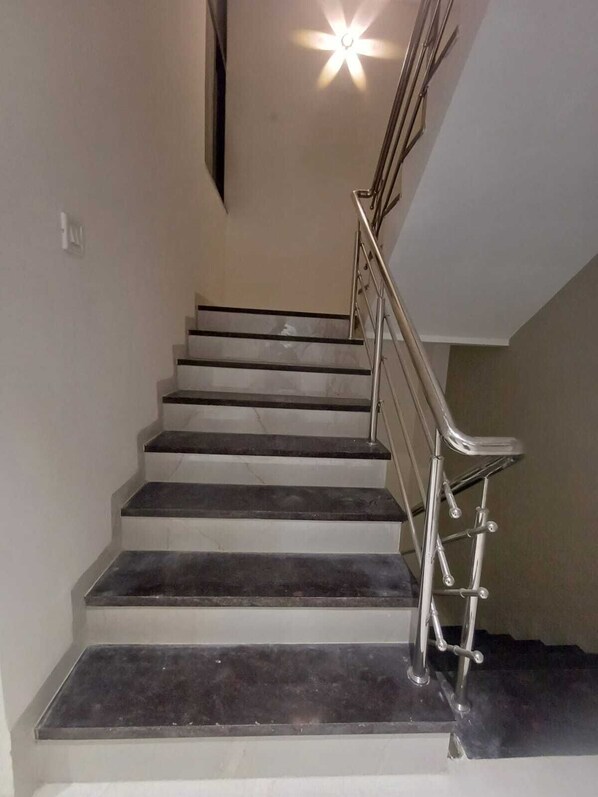 A staircase with a metal handrail and a light fixture at the top. - JMB Hotel Height (Indore)
